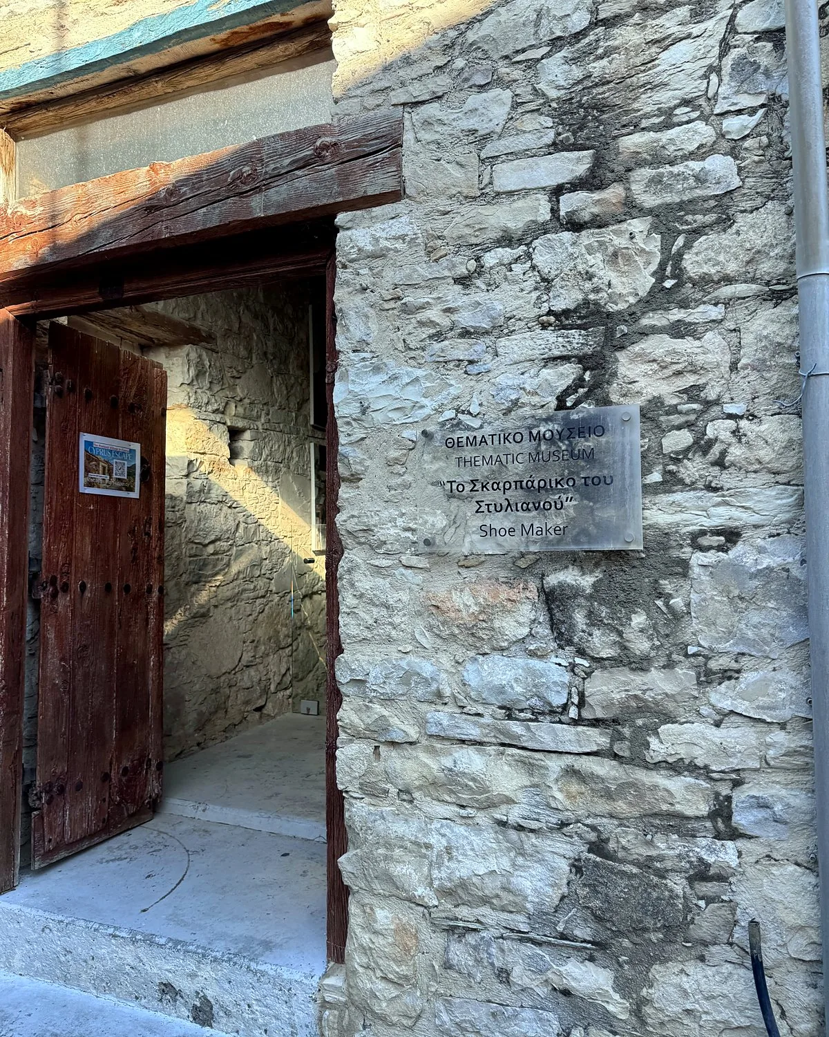 Lania village, Cyprus: we walked into every open door Open wooden door and stone wall with a plaque for the shoemaker's workshop museum in Lania, Cyprus