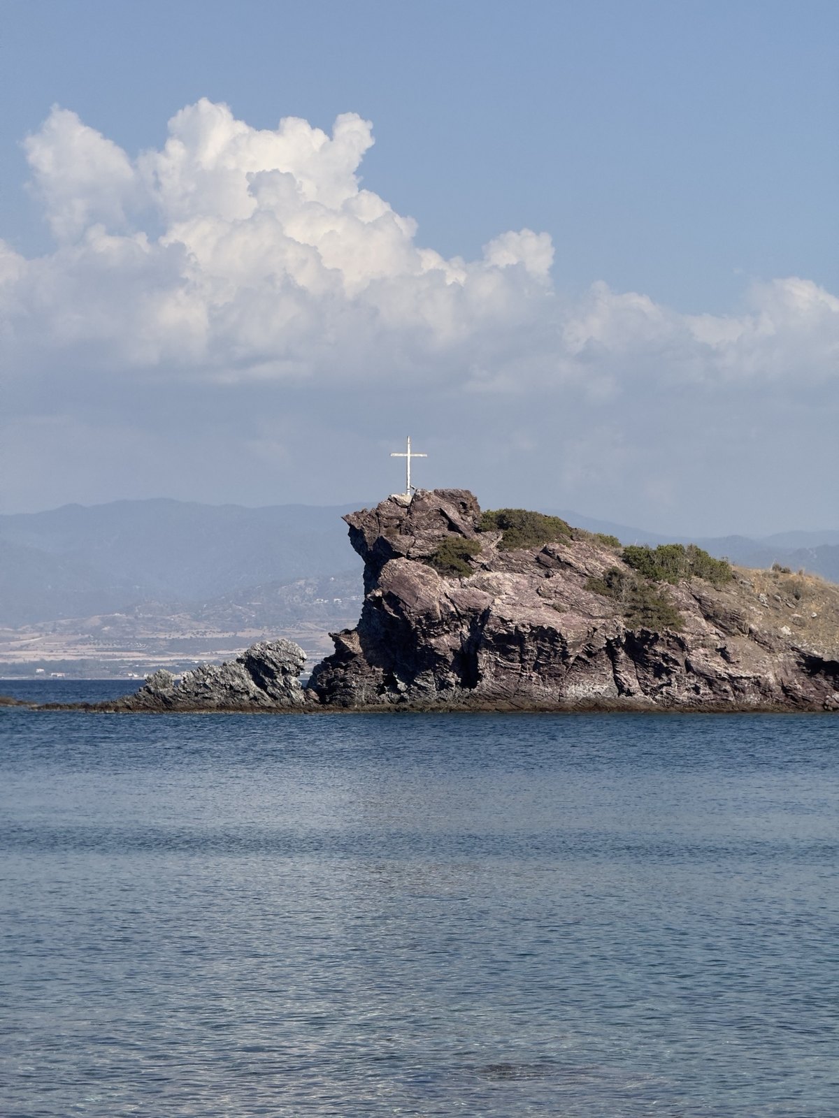 Rock with a white cross across the bay near the Baths of Aphrodite