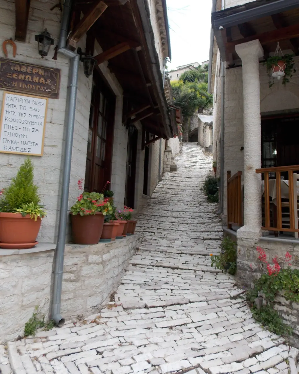Narrow white stone-paved lane climbing between old stone houses in Syrrako
